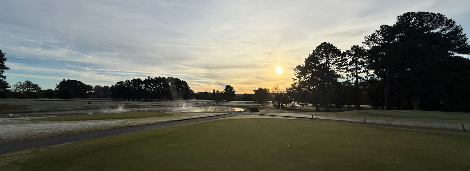 Golf Course Green at sunrise with cart path and trees